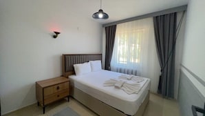 Una camera da letto con un letto, un comodino, una lampada e una finestra con tende.
