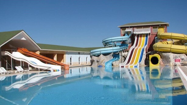 Una piscina con scivoli acquatici e un edificio con tetto spiovente.