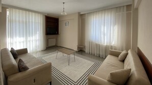 Un soggiorno moderno con due divani, un tavolino da caffè e una televisione.