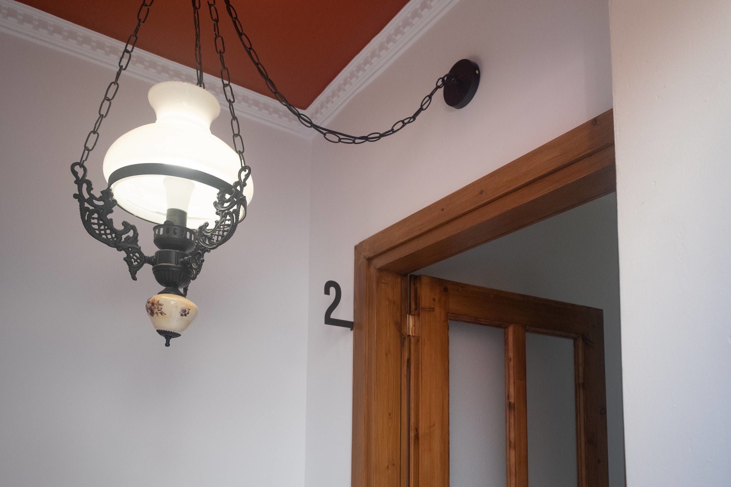 Une pièce avec un luminaire suspendu et un cadre de porte en bois.