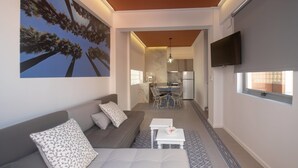 A modern living room with a sofa, a coffee table, and a dining area with a table and chairs. - Athenian Yard Suites (Athens)