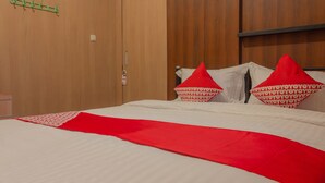 Una habitación de hotel con una cama, un armario de madera y un perchero verde.