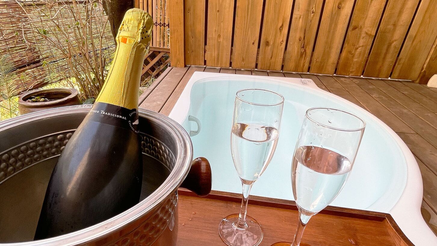 Un jacuzzi con dos vasos de agua, una botella de champán y un balde.