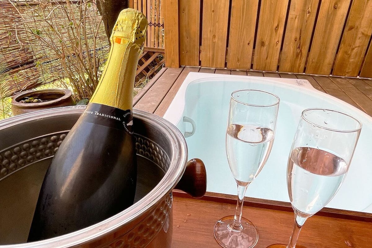 Un jacuzzi con dos vasos de agua, una botella de champán y un balde.