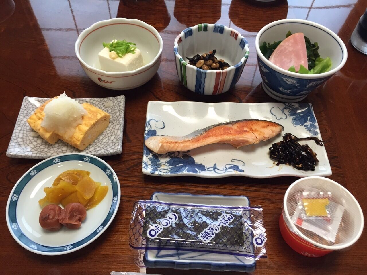 A table with various dishes including tofu, fish, and pickled vegetables.