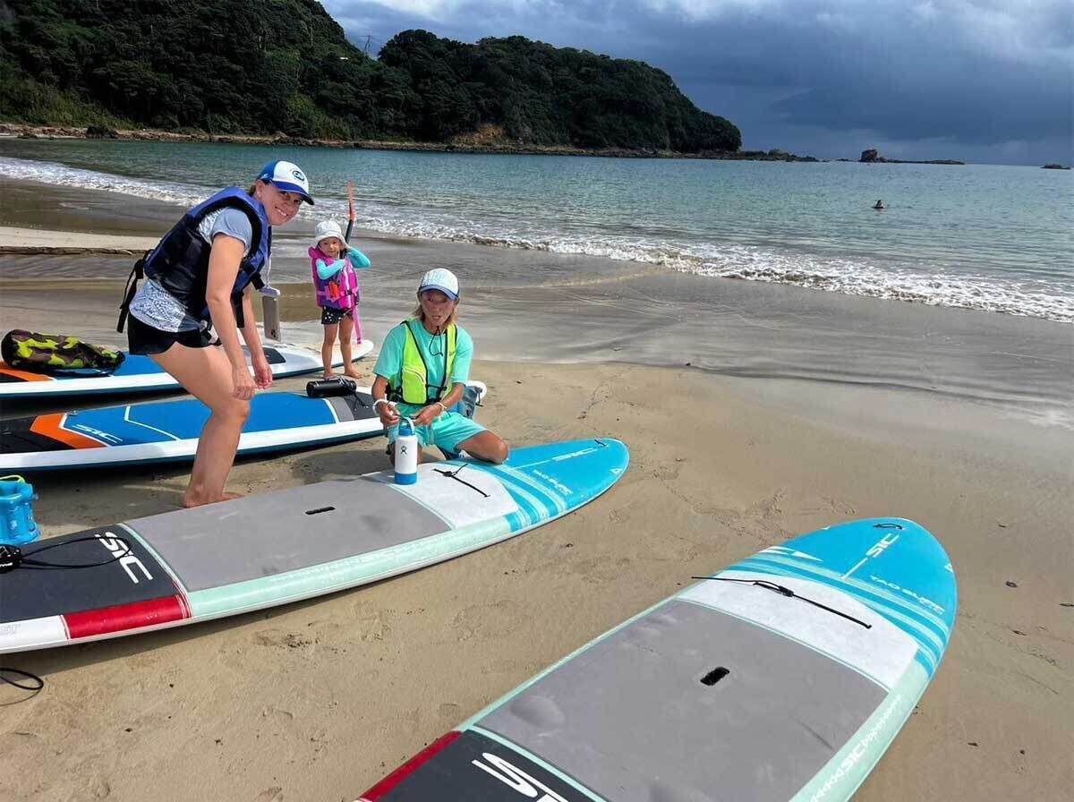 Una playa con tablas de surf y una persona en un traje de neopreno.