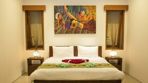 Una cama bien hecha con sábanas blancas, dos mesitas de noche con lámparas y un cuadro colorido sobre la cama.