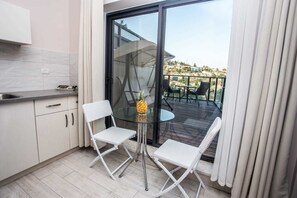 A compact kitchen with white cabinets and a small dining table with two chairs. A pineapple is on the table. - HApalmach 35 (Safed)