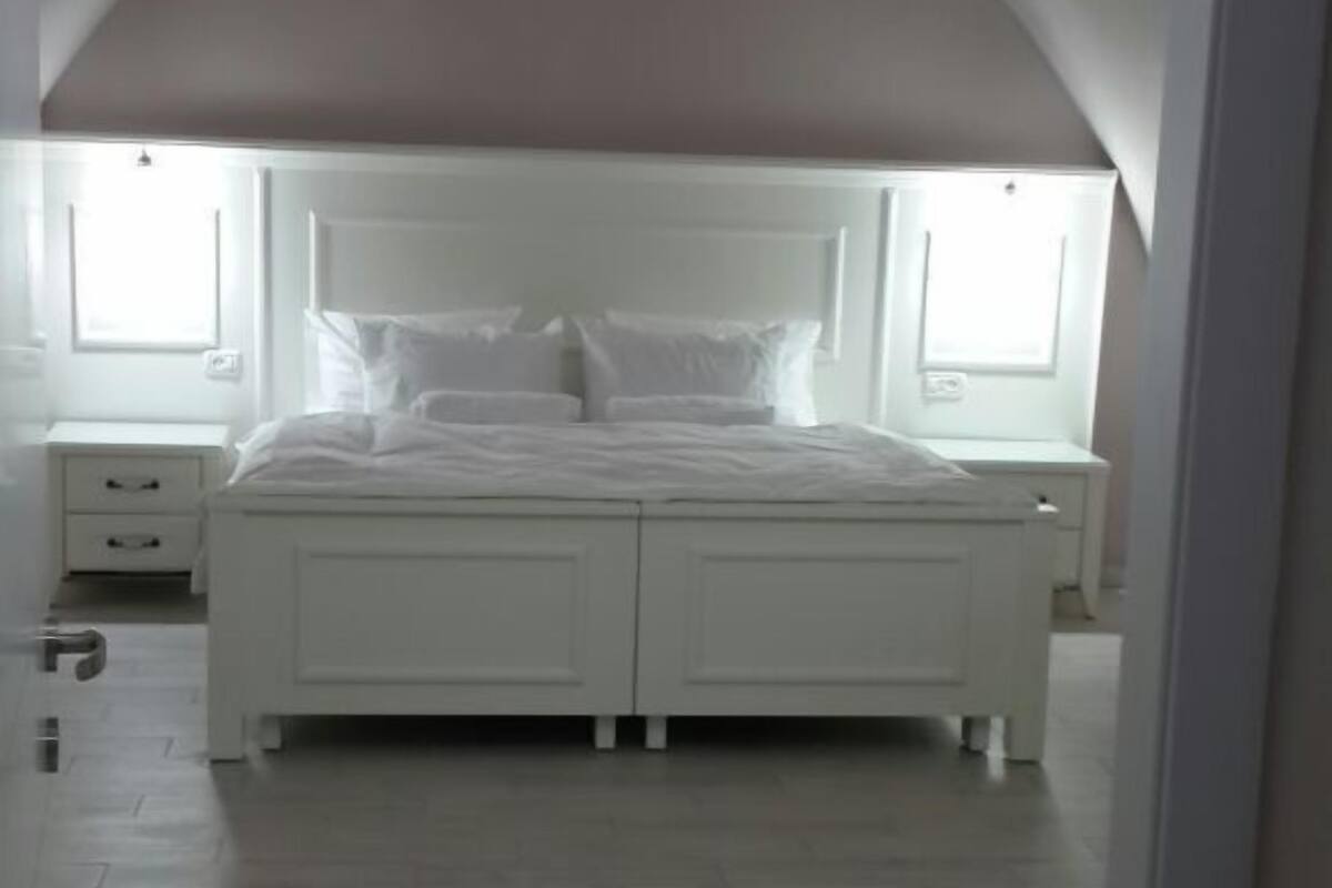 Un dormitorio con una cama grande, dos mesitas de noche y un techo inclinado.