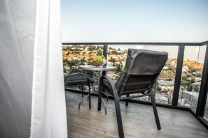 A balcony with a table and chairs, a bowl of fruit, and a view of a cityscape. - HApalmach 35 (Safed)