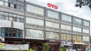 Ein Hotel mit einem großen 'OYO'-Schild, mehreren Stockwerken und verschiedenen Geschäften und Restaurants im Erdgeschoss.