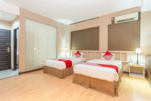 Une chambre d’hôtel avec deux lits, une armoire, une table de chevet avec une lampe et un appareil de climatisation.
