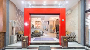 Ein Hotel mit Eingang, einem roten Bogen, gemusterten Sofas und einer Rezeption.