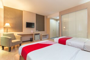 A hotel room with two beds, a desk, a chair, a TV, and a wardrobe. - OYO 663 Hotel Sejati (Balikpapan)