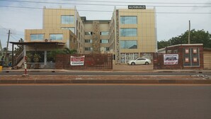 Un edificio de varios pisos con un letrero que dice "AUSBUILD GHANA" y un coche estacionado al frente.
