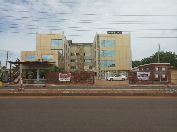 A multi-story building with a sign reading "AUSBUILD GHANA" and a car parked in front. - Ausbuild (Accra)