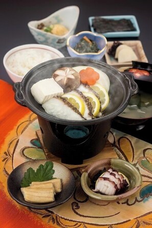 Una olla japonesa tradicional con diversos ingredientes, rodeada de pequeños cuencos con acompañamientos.