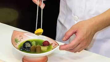 A person in a white chef's coat holding chopsticks over a bowl of food.