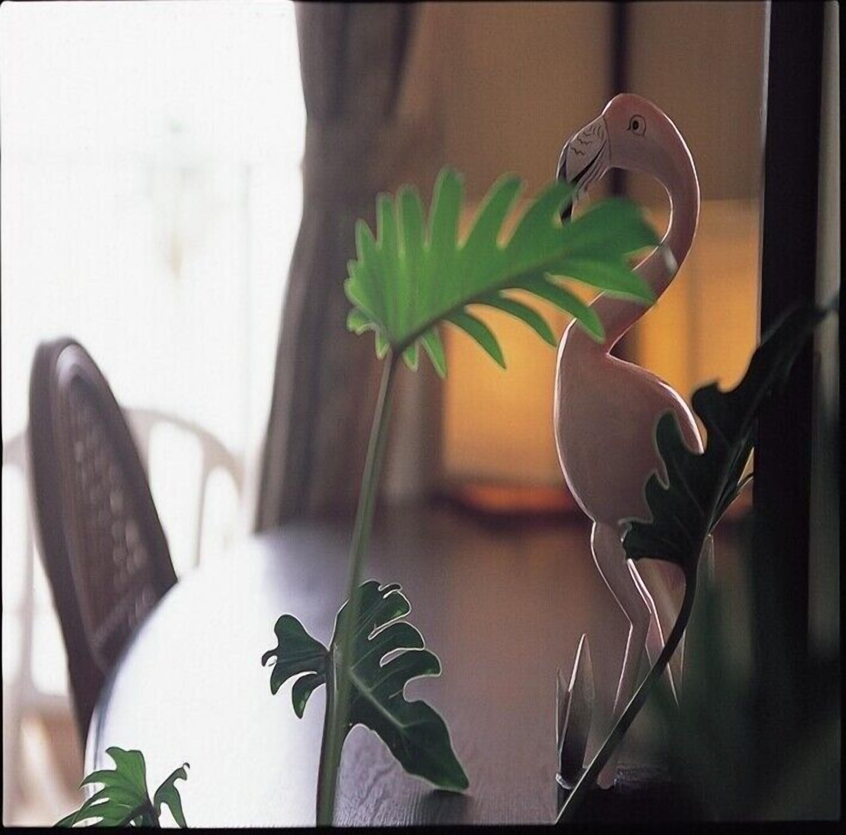 Een eettafel met een decoratief beeld van een vogel en een groot, groen blad.