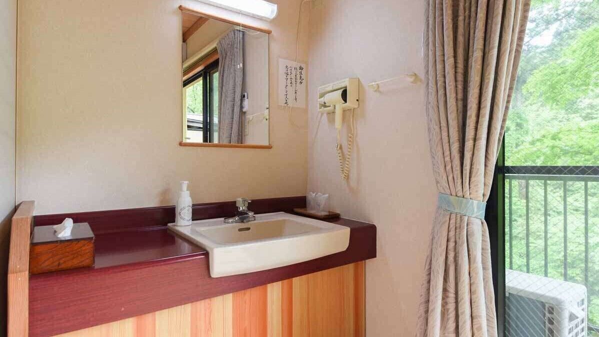A bathroom with a sink, mirror, and a telephone.