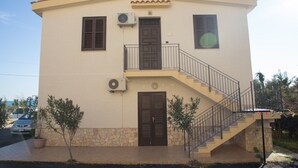 Un edificio a due piani con una scala, una porta e un condizionatore d'aria.