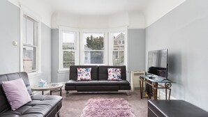 A modern living room with a leather sofa, a glass coffee table, and a fluffy rug.
