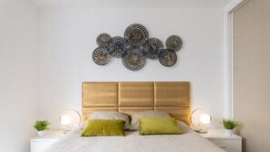 Une chambre à coucher comprenant un lit, deux tables de chevet, un élément décoratif fixé au mur et deux lampes murales.