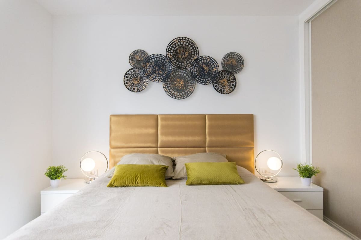 A bedroom with a bed, two bedside tables, and a decorative wall piece.
