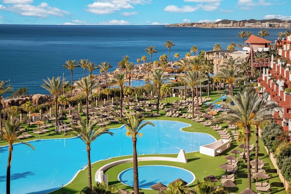 A resort with a large pool, palm trees, and a view of the ocean.