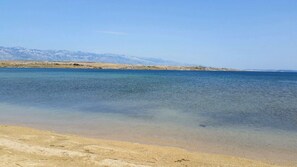 Uma praia com águas cristalinas e montanhas ao longe.
