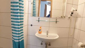 A bathroom with a white sink, a mirror, a towel rack, and a shower curtain.