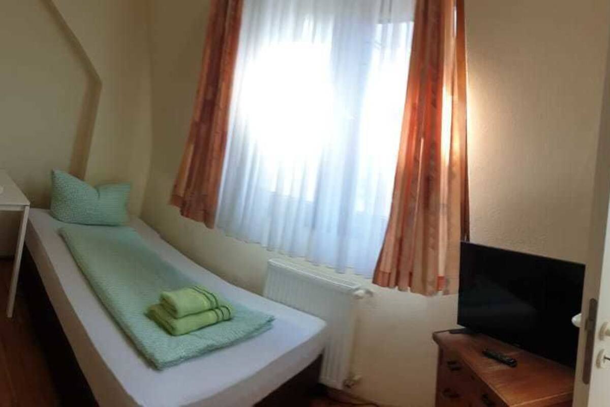 Una habitación pequeña y funcional con dos camas individuales, una mesita y una silla.