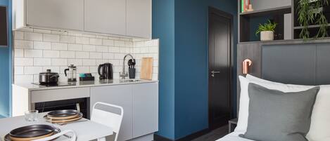 A modern room with a kitchen area, a dining table, and a bed.