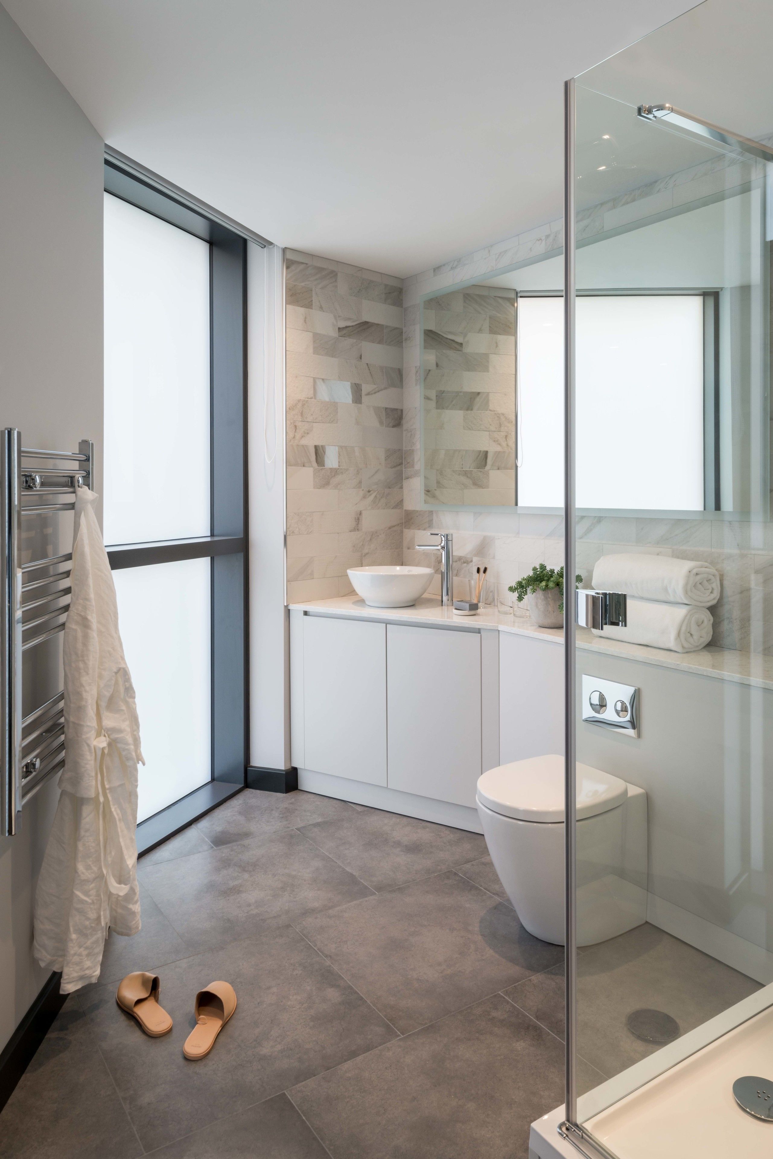 A modern bathroom with a glass shower enclosure, a white sink, and a toilet.
