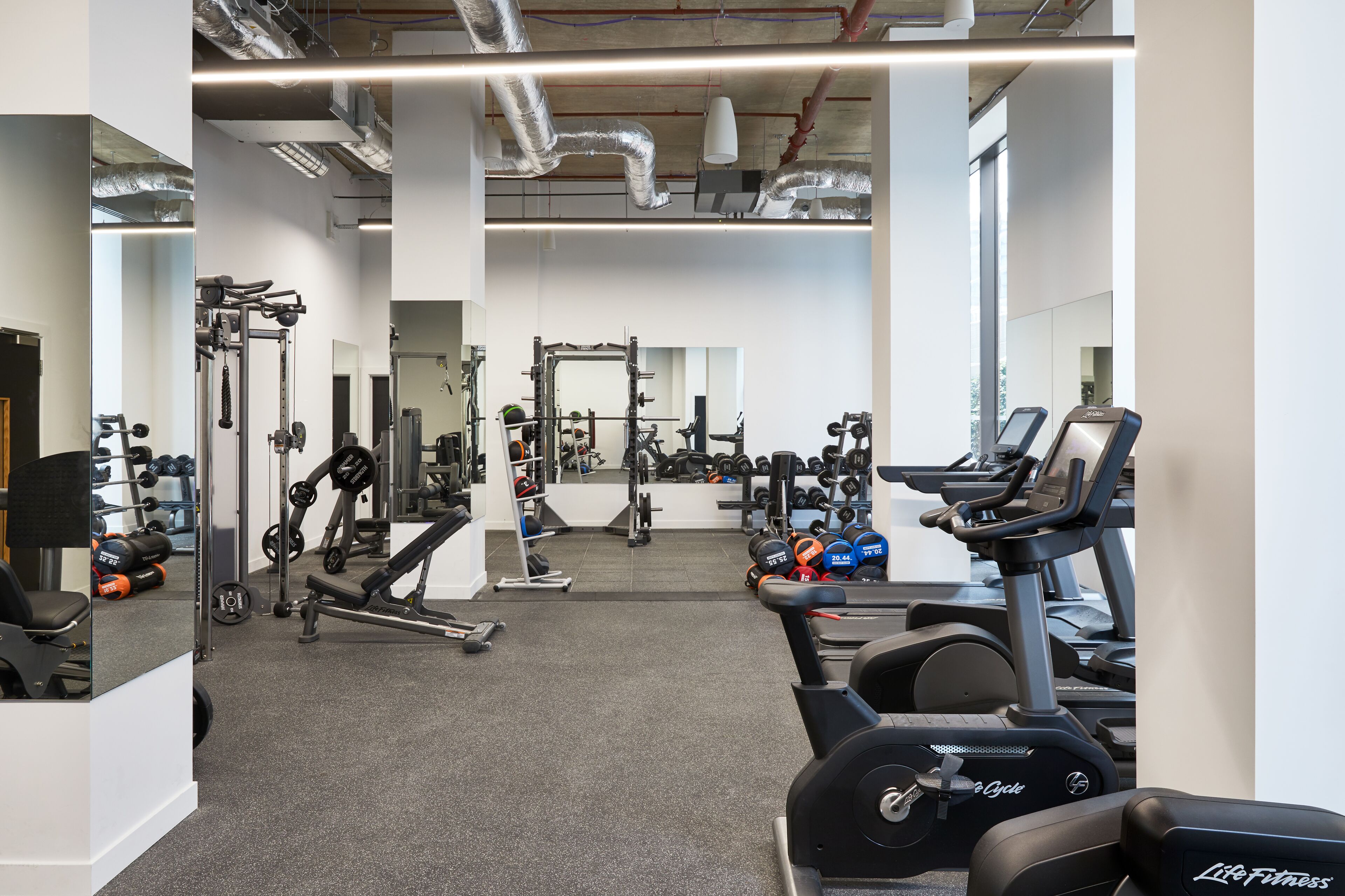 A gym with cardio machines, weightlifting equipment, and mirrors.