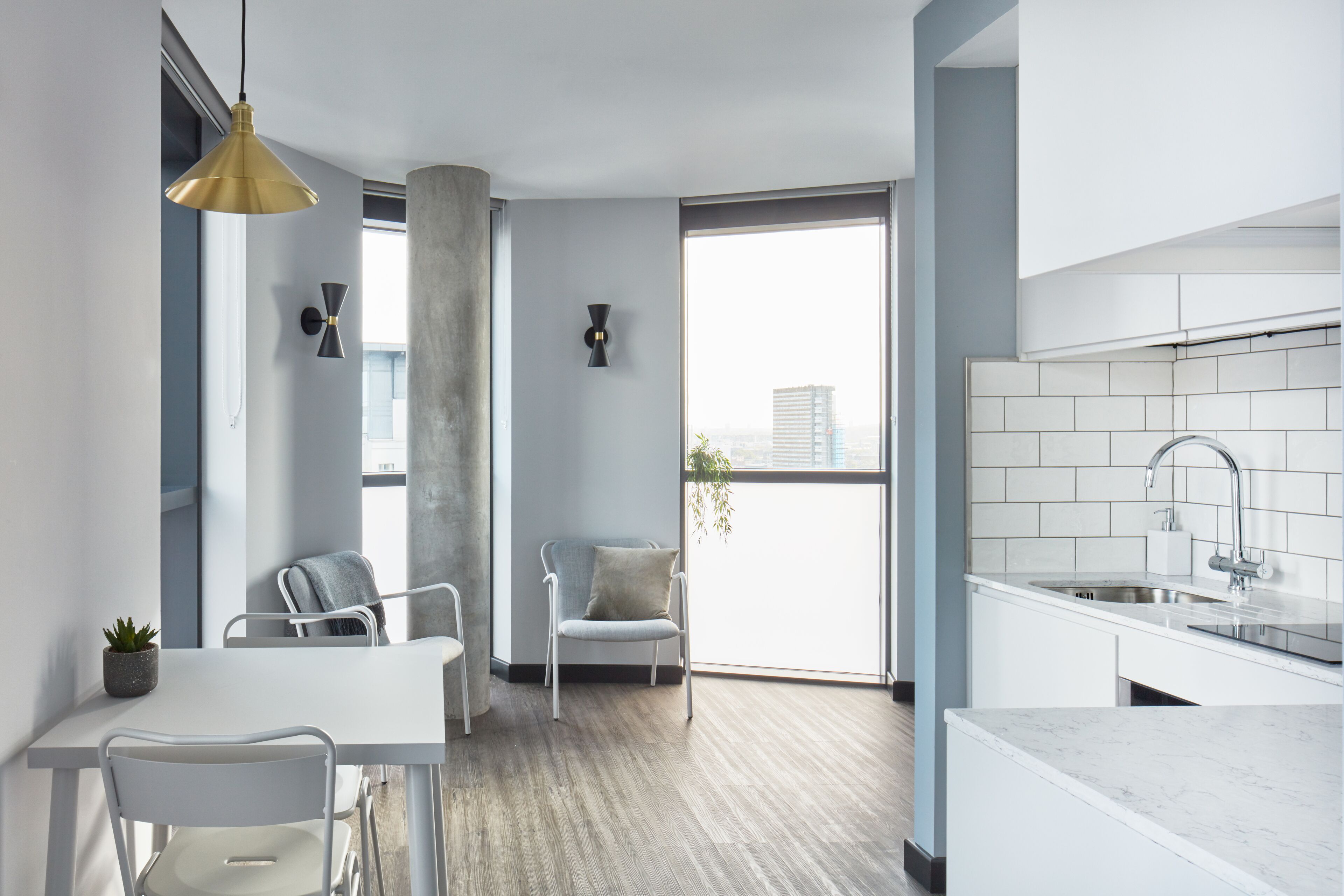 A modern kitchen with white cabinetry, a large window, and a view of the city.