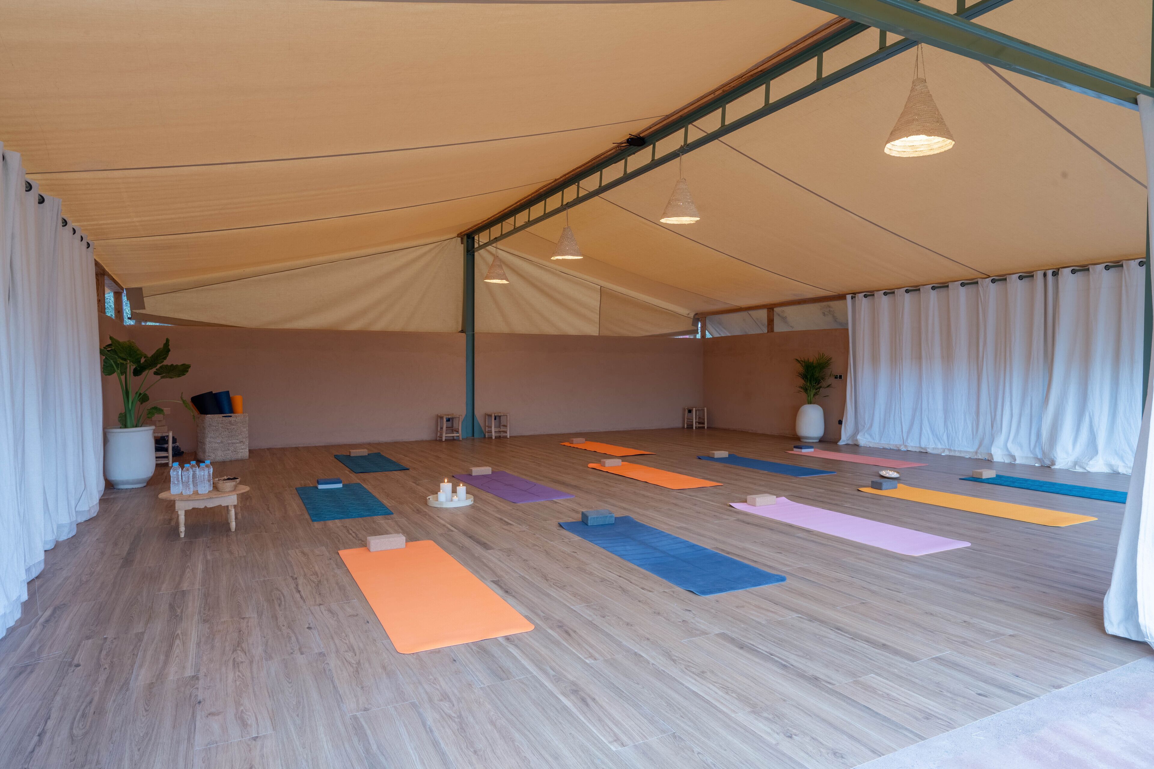 A spacious indoor area with a high ceiling, wooden flooring, and multiple yoga mats arranged for use.