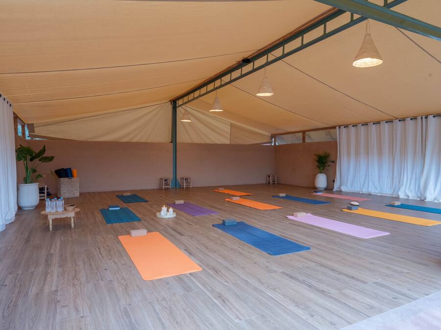 A spacious indoor area with a high ceiling, wooden flooring, and multiple yoga mats arranged for use.