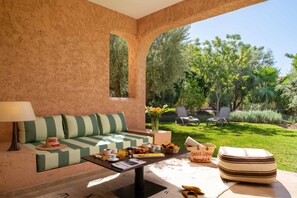 A cozy room with a sofa, a coffee table, and a view of a lush garden.