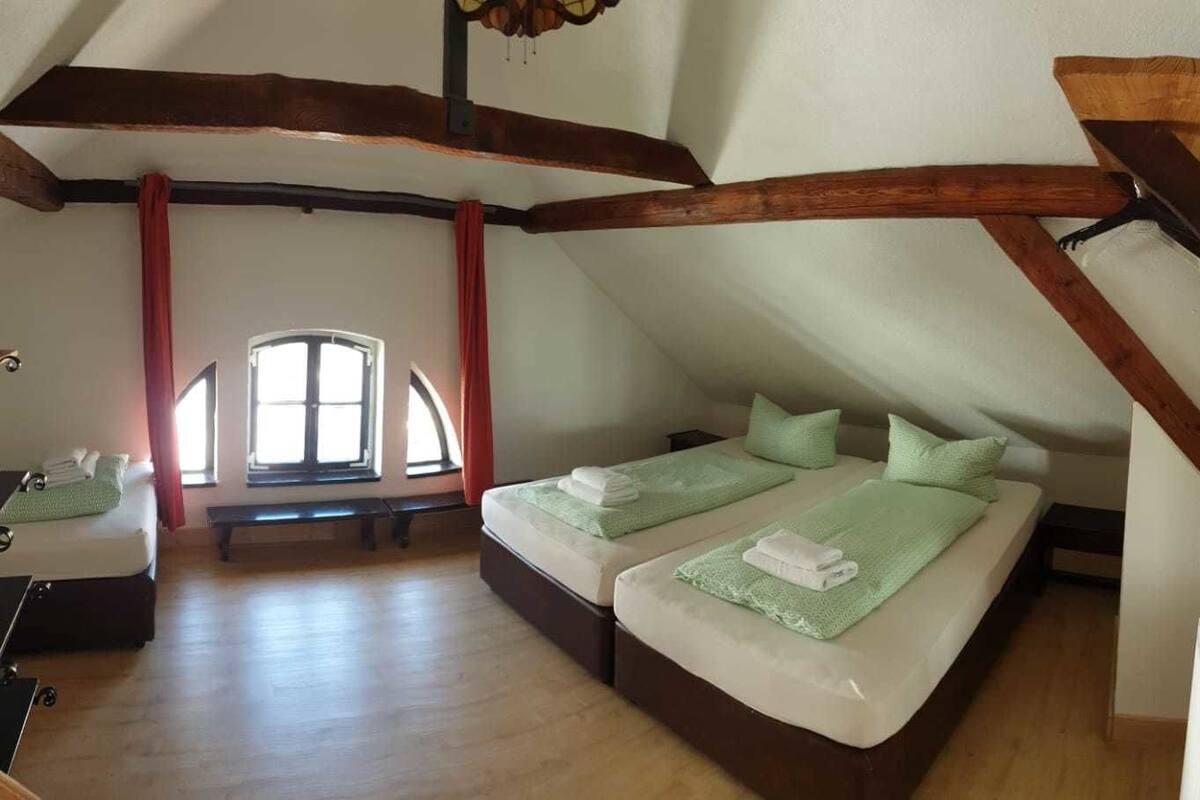 Ein Schlafzimmer mit zwei Betten, Holzbalken, einer Bank und einem Fenster.