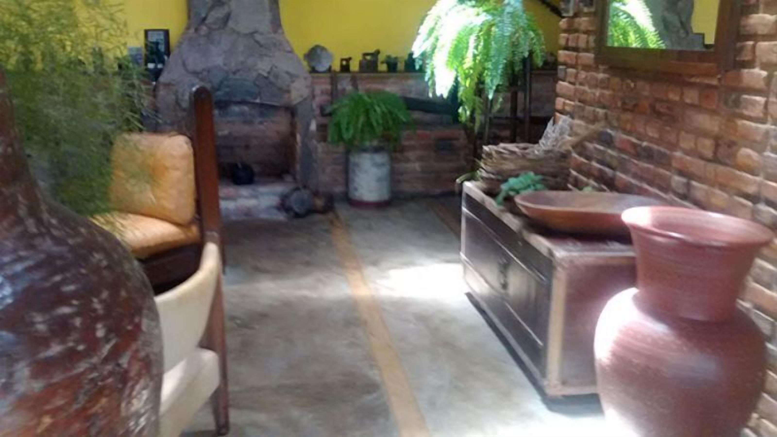 A rustic interior with a stone fireplace, a brick wall, and a seating area with a chair and a table.