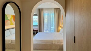 A hotel room with a large bed, a mirror, and a view of the outside. - Datca Deniz Hotel (Datça)