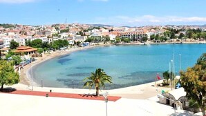 A coastal town with a clear blue bay, sandy beach, and a palm tree in the foreground. - Datca Deniz Hotel (Datça)