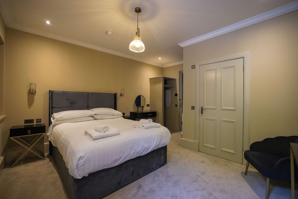 Un dormitorio con una cama grande, una mesita de noche, un armario y una puerta.