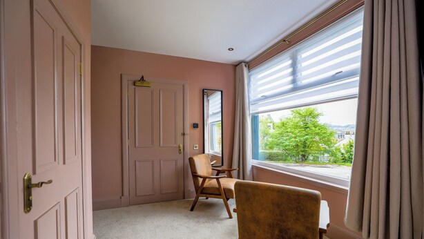 A room with a large window, a chair, a door, and a mirror. - Dalrigh House (Oban)
