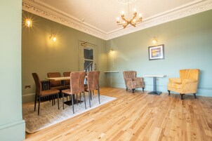 A dining area with a wooden table and chairs, a chandelier, and a framed picture on the wall.