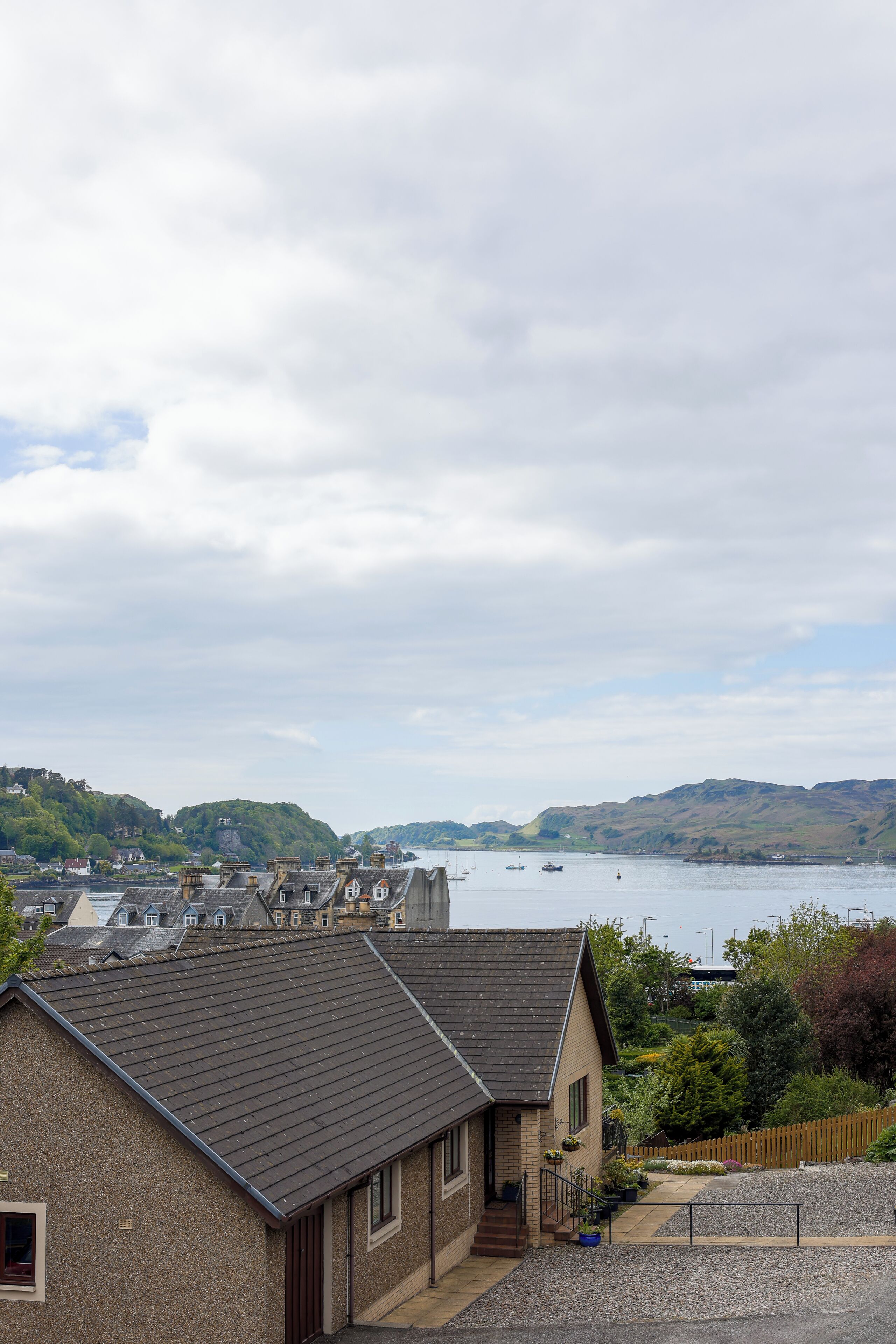 A coastal house with a view of the sea and hills.