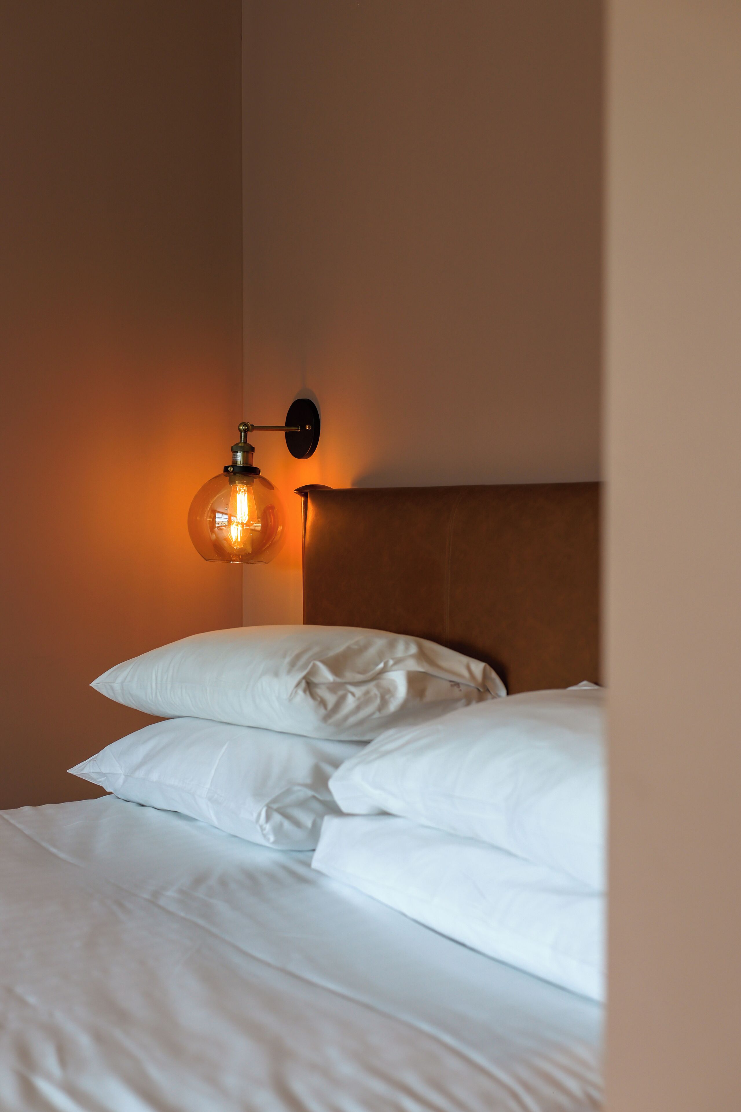 Una cama bien hecha con sábanas blancas y un cabecero de madera.