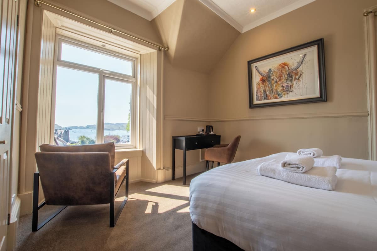 Una habitación de hotel con una cama grande, un escritorio, una silla y una ventana con vistas.