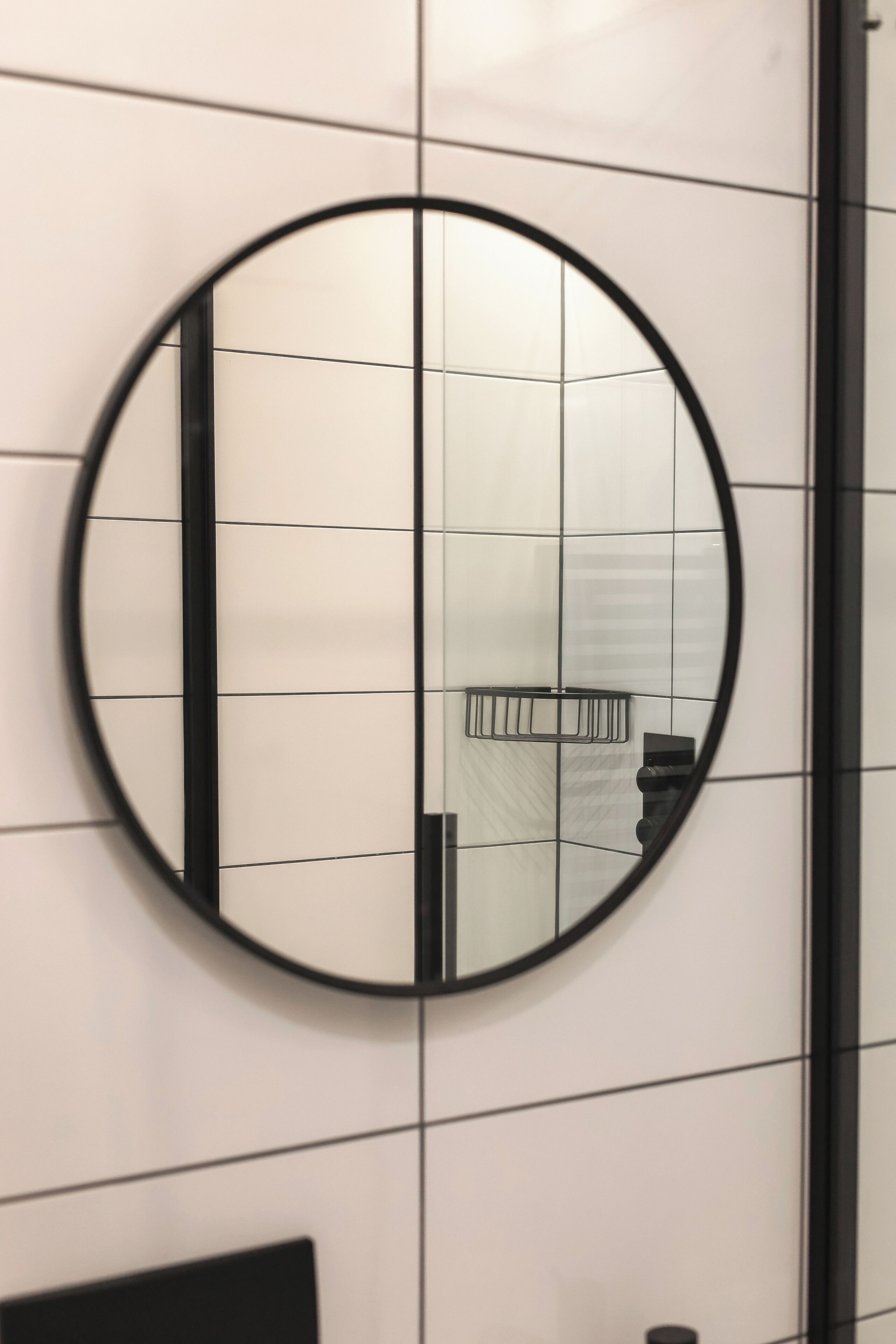A circular mirror on a tiled wall.